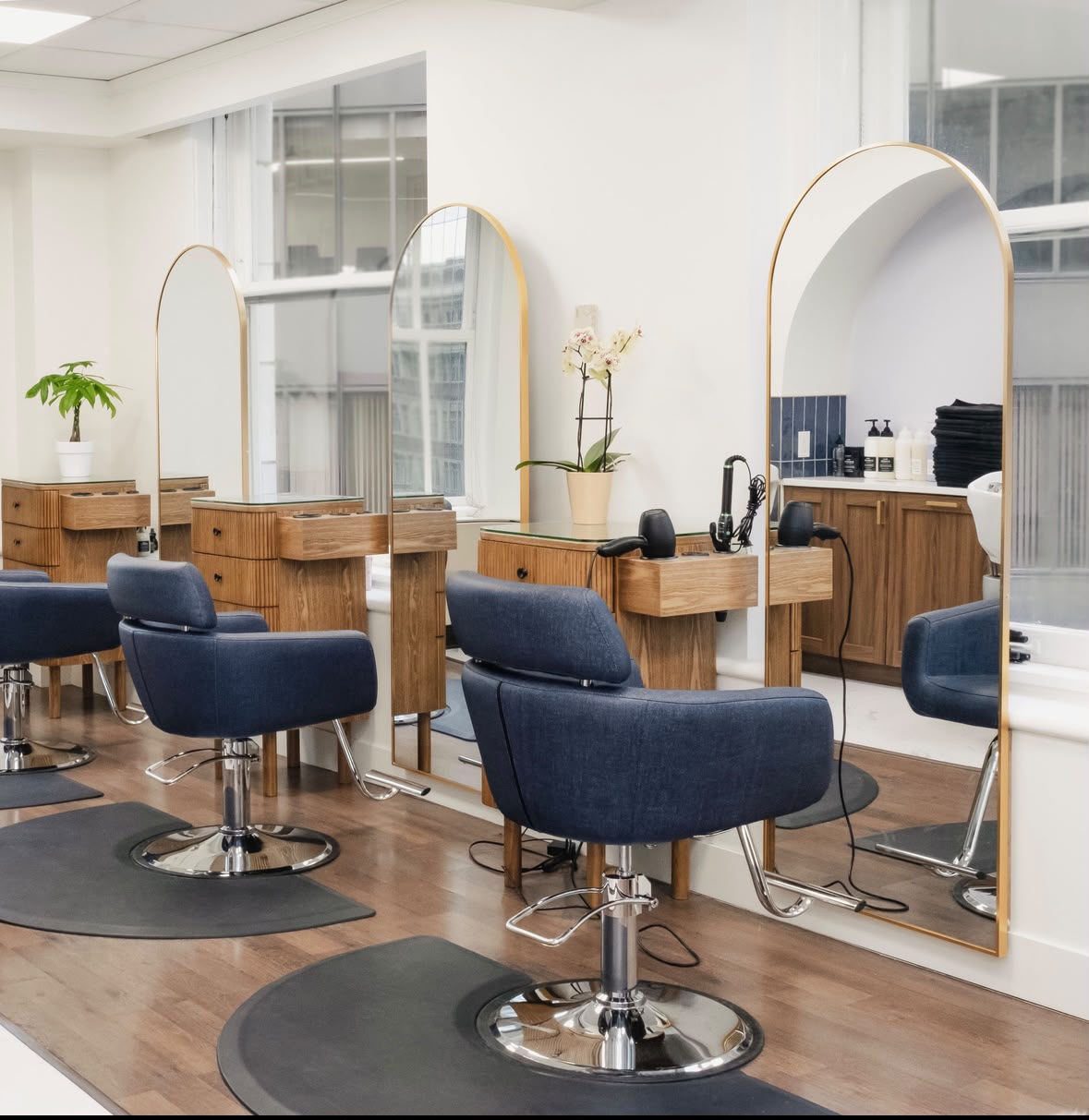 Level Headed Salon styling area, arched gold-frame mirrors and walnut wood stations